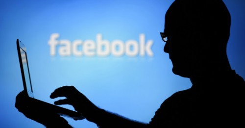 Facebook Berikan Peringatan Akun yang Tengah Dimata-matai Pemerintah 1 A man is silhouetted against a video screen with an Facebook logo as he poses with an Dell laptop in this photo illustration taken in the central Bosnian town of Zenica, August 14, 2013. REUTERS/Dado Ruvic (BOSNIA AND HERZEGOVINA - Tags: BUSINESS TELECOMS) - RTX12L6I